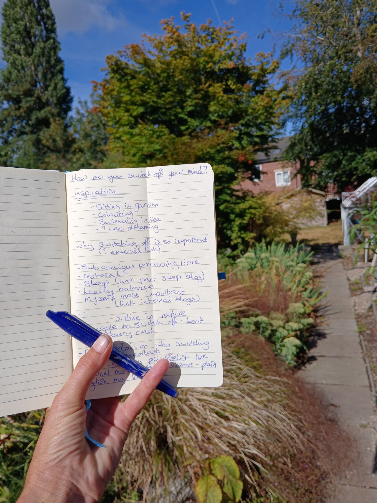 Notebook with handwritten blog ideas in a sunny garden, showing how planning away from a desk can boost productivity.