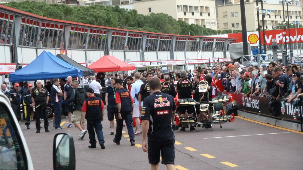 Formula 1 teams and equipment in the busy Monaco Grand Prix pit lane, showing the teamwork behind motor racing.