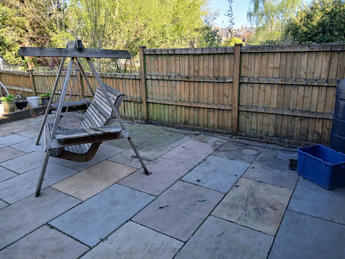 Wooden garden swing seat on a stone patio before cleaning, showing an everyday task that inspired a different way of thinking.