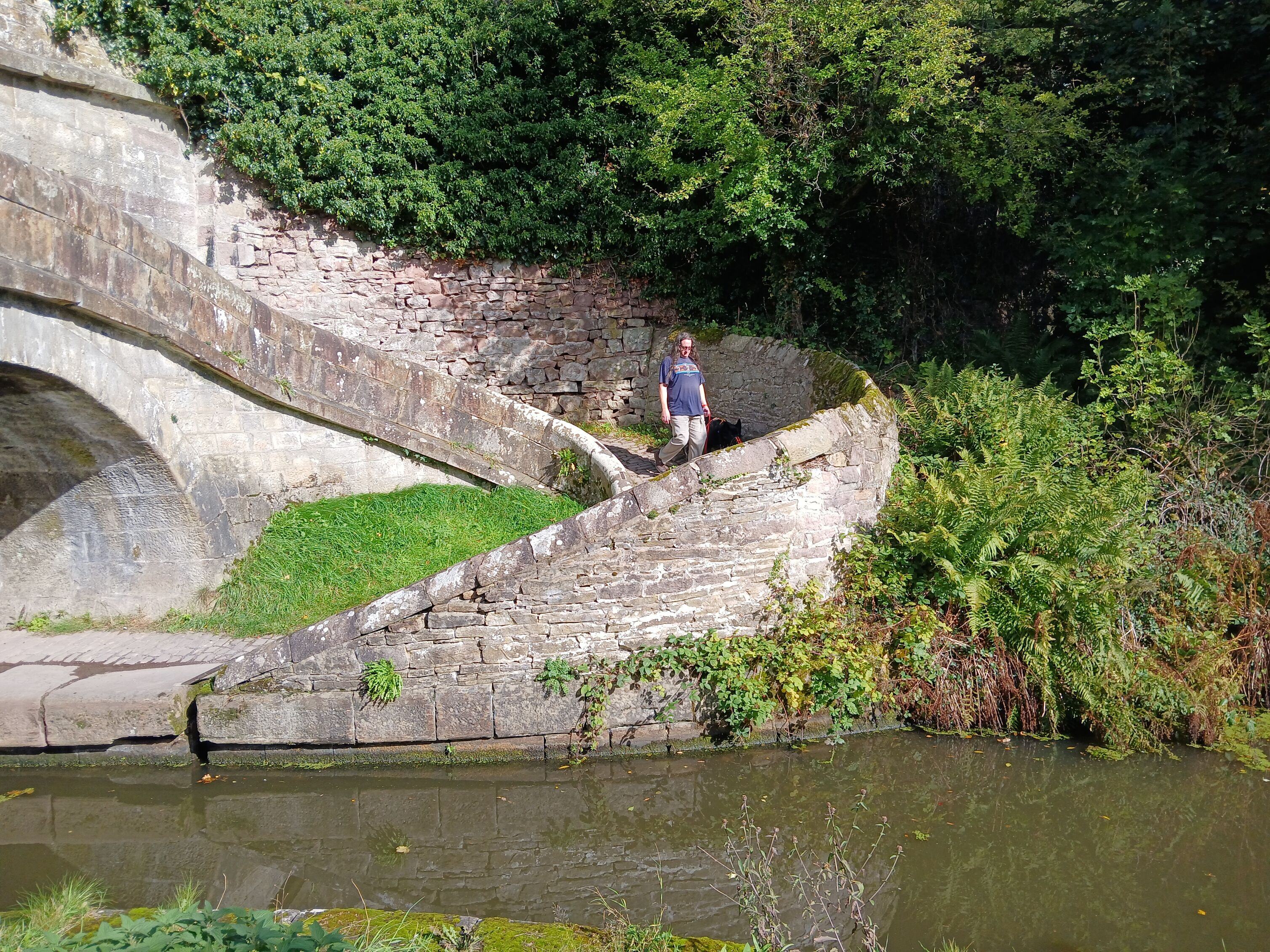 Winding stone pathway beside a canal, showing a person walking along the curved route